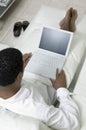 Man reclining on sofa using laptop high angle view