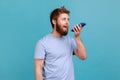 Man recording voice message, talking to online assistant at his smartphone holding phone near mouth. Royalty Free Stock Photo