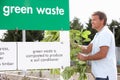 Man At Recycling Centre Disposing Of Garden Waste