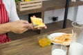 Man in red apron spreading sweet orange peel jam on toast with sun icon over table Royalty Free Stock Photo