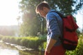 Man with red backpack walking in forest near river alone. Royalty Free Stock Photo