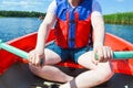 A man in a red boat, shorts and a life jacket is paddling with oars on a boat for a walk on the water of the lake river sea Royalty Free Stock Photo