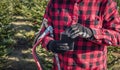 Man in red plaid shirt holding saw and flask at christmas tree f Royalty Free Stock Photo