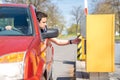 A man in a red car gets a ticket in a parking meter