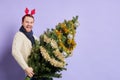 Man in red christmas horn holding Christmas tree