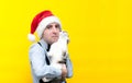 Man in red christmas santa hat, blue shirt and black suspender holding cute white with brown tabby cat and looking at camera Royalty Free Stock Photo