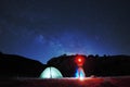 Man with red headlamp looking in camera near lighting tent, on background starry sky Royalty Free Stock Photo