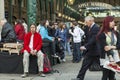 A man in a red jacket and camouflage pants sits on a bench in front of the Apple Market at Covent Garden