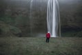 Man with red jacket standing infront of the famous Seljalandsfoss waterfall in Iceland in the rain Royalty Free Stock Photo