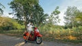 Man on red motorbike in white clothes drive on forest road trail trip. One men caucasian tourist go on scooter, nearby Royalty Free Stock Photo