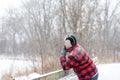 Man looking out over wooden bridge in snowfall