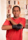 Man in red shirt wearing wrist brace support on right hand posing for camera, holding his shoulder with other arm Royalty Free Stock Photo