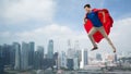 Man in red superhero cape flying in air over city Royalty Free Stock Photo