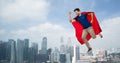 Man in red superhero cape flying in air over city Royalty Free Stock Photo