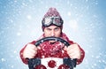 Man in a red sweater, scarf and hat holds a steering wheel in his hands and drives a car through the snow Royalty Free Stock Photo