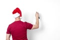 A man in a red t-shirt and Santa Claus hat is painting on a white wall from a spray can of paint, back view. Royalty Free Stock Photo