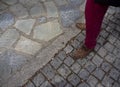 A man in red trousers and brown shoes stands on a tiled and natural stone sidewalk in Greece Royalty Free Stock Photo