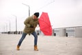 Man with red umbrella caught in gust of wind outdoors