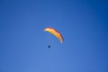 A man on a red yellow white paraglide in a clear blue sky Royalty Free Stock Photo