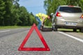 Man in reflective vest changing tire after breakdown Royalty Free Stock Photo