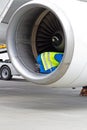 A man in a reflective vest. Technician sits in a turbine and checks the plane's engine before flying. Aviation