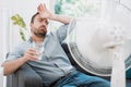 Man refreshing with electric fan against summer heat wave