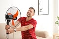 Man refreshing from heat in front of fan Royalty Free Stock Photo