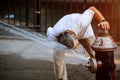 Man is refreshing himself in Public square summer high temperature with Fire hydrant water