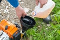 A man refuels a lawn mower& x27;s gasoline engine from a plastic tank