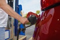 Man refuses his red car with gasoline at a gas station. Hand and black refueling gun close up Royalty Free Stock Photo