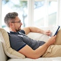 Man, relax and tablet on living room sofa, reading and social media for video, game or movies in home. Mature guy Royalty Free Stock Photo