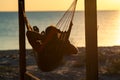 Man relaxes in a hammock on abandoned bungalow veranda