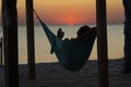 Man relaxes in a hammock on abandoned bungalow veranda