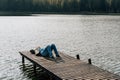 A man relaxes lying on a wooden boat dock on a lake in autumn Royalty Free Stock Photo