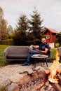 Man relaxing by a backyard fire pit Royalty Free Stock Photo