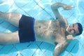 Man relaxing at the bottom of swimming pool