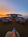A man is relaxing on the deck of a ship at sunset, stretching his legs on a sunbed. Royalty Free Stock Photo