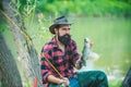 Man relaxing and fishing by lakeside. Hobby sport activity. Man fishing on the lake. Portrait of cheerful bearded man Royalty Free Stock Photo