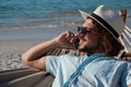 Man relaxing on hammock and talking on mobile phone on the beach Royalty Free Stock Photo