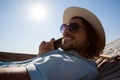 Man relaxing on hammock and talking on mobile phone on the beach Royalty Free Stock Photo