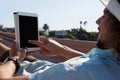 Man relaxing on hammock and using digital tablet on the beach Royalty Free Stock Photo