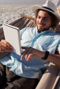 Man relaxing on hammock and using digital tablet on the beach Royalty Free Stock Photo