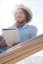 Man relaxing on hammock and using digital tablet on the beach Royalty Free Stock Photo