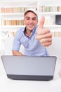 Man relaxing at home with laptop computer showing thumbs up Royalty Free Stock Photo