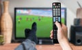 Man is relaxing with legs on table and is watching football match on tv.