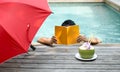 Man relaxing reading a book and having coconut juice by the swi