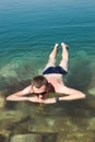 Man relaxing on water surface Dead Sea. Tourism recreation, healthy lifestyle concept. Peaceful meditation Royalty Free Stock Photo