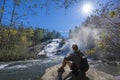 Man relaxing by waterfall on hiking trip. Royalty Free Stock Photo