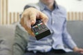 The man with remote control in hand watching the sports channel and presses the button on the remote control. Remote control in Royalty Free Stock Photo