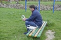 A man with a remote control quadroopter in his hands is sitting on a bench. White quadroopter prepare for flight. Royalty Free Stock Photo